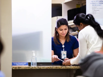 A woman checks in for an appointment at her local health clinic