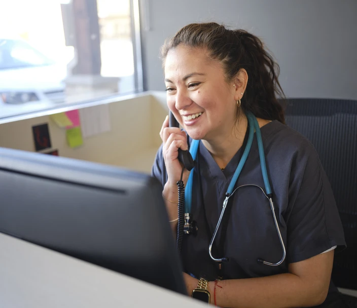 A healthcare worker answers the phone with a smile