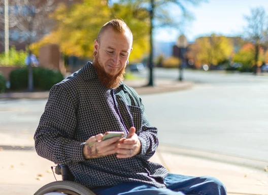 Adult man using a wheelchair checks his phone for service locations near him