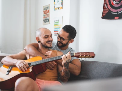 Gay couple playing guitar and singing on the sofa