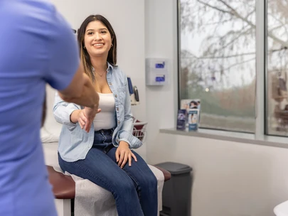 A clinic nurse greets a young Latina woman who has come in for HIV testing